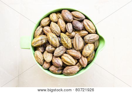 yellow myrobalan stored in a jug on a plain background