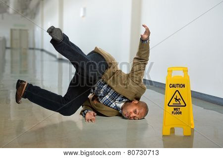 African American businessman falling on wet floor in office