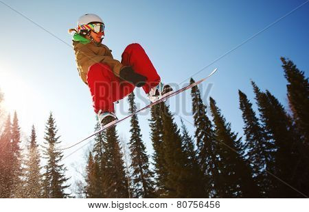 Snowboarder jumping through air with deep blue sky in background