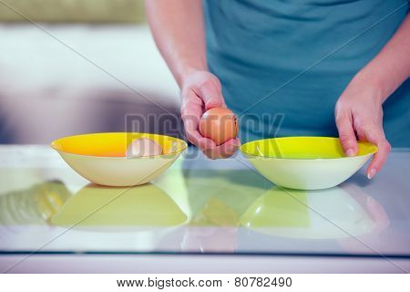 Female hands separating yolk and white of a cracked egg