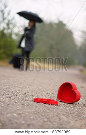 Heart on the road and woman with luggage and umbrella