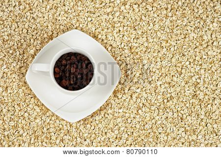 Coffee cup full of raisins with oat flakes in the background