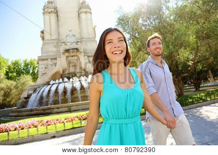 Couple walking on Plaza de Espana Madrid a popular tourist destination landmark. Romantic couple visiting Spanish tourists attractions sightseeing in Madrid, Spain. Asian woman, Caucasian man.