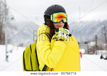 Smiling young gigl holding snowboard