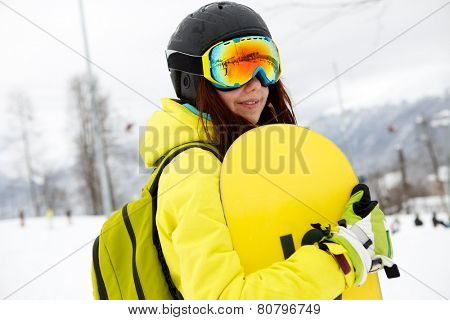 Smiling young gigl holding snowboard