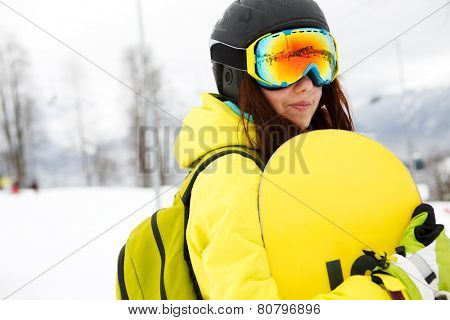Smiling young gigl holding snowboard