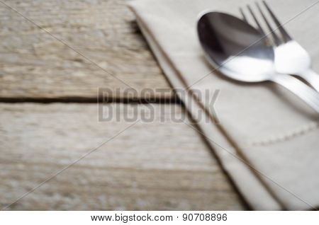 blurred background with a napkin and cutlery on wooden table