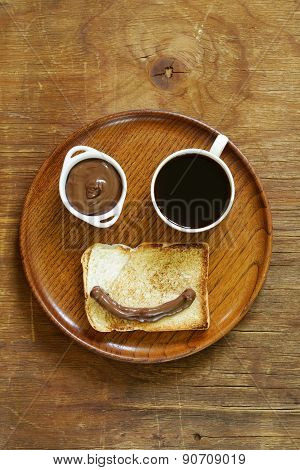 breakfast serving funny face on the plate (toast, chocolate spread and coffee)