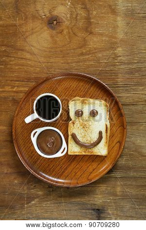 breakfast serving funny face on the plate (toast, chocolate spread and coffee)