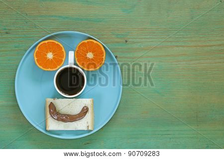 breakfast serving funny face on the plate (toast, chocolate spread and orange)