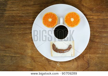 breakfast serving funny face on the plate (toast, chocolate spread and orange)