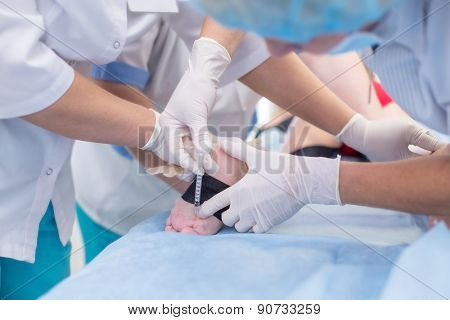 a group of doctors injections boy on medical table
