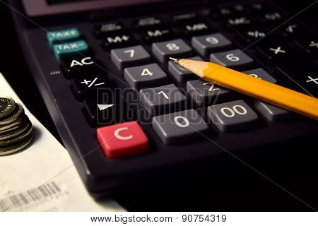 Pencil and Calculator beside the Bill and Coins
