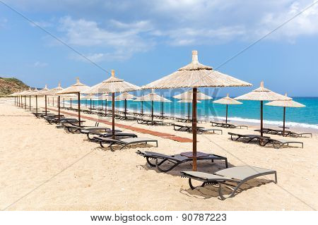 Many reed beach umbrellas in a row on empty beach near sea