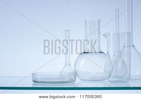 Assorted empty laboratory glassware, test-tubes. Blue tone medical background. Copy space for text.