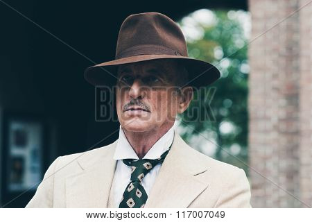 Close-up Of Senior Dandy With Hat And Suit In Front Of Gate.