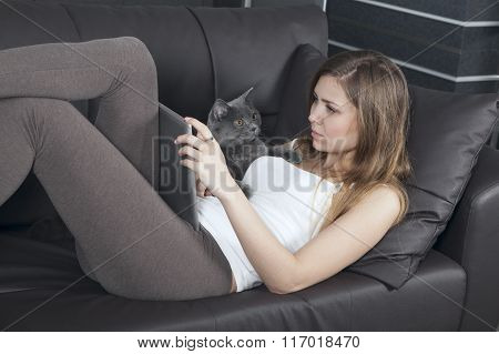 woman resting on a sofa with tablet computer