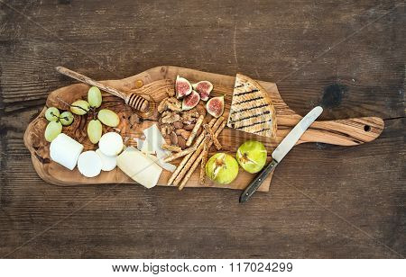 Wine appetizers set: cheese selection, honey, grapes, almonds, walnuts, bread sticks, figs on olive