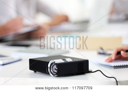 Black projector on white table for business presentation in the foreground