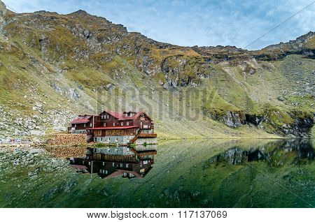 BALEA CHALET, ROMANIA - SEPTEMBER 19 2015: view of Balea Lake cottage on Fagaras Mountains, Romanians Carpathians. The image of the chalet is reflected in the lake.