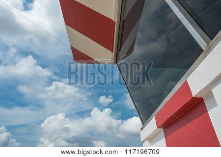 Air traffic control tower with red and white paint and scatterd cloud