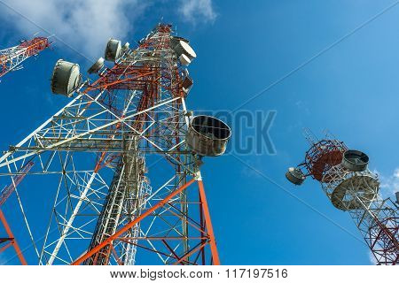 Three big radio mast attached with many dishes with blue sky