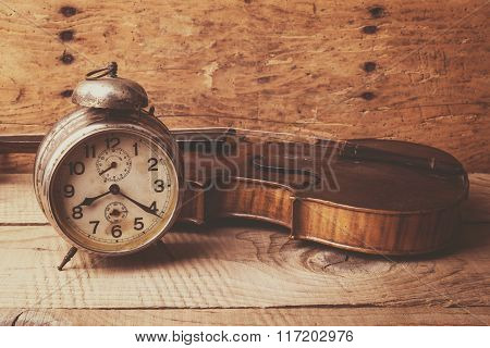 Antique Clock And Old Violin Over Vintage Wooden Table