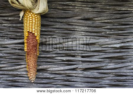 Ear Of Corn With Dry Leaves Against A Wooden Background