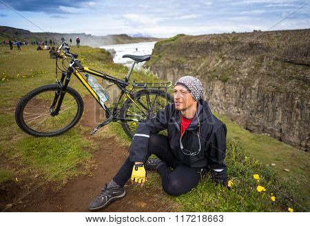Happy biker on backdrop of waterfall in mountains Iceland