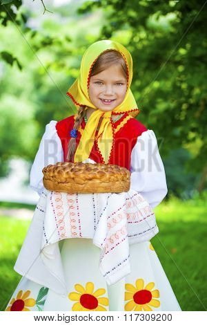 Little girl is dressed in the Russian national dress. She holds in his hands the fresh loaf. It is a custom to meet the guests.