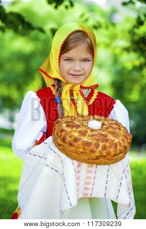 Little girl is dressed in the Russian national dress. She holds in his hands the fresh loaf. It is a custom to meet the guests.