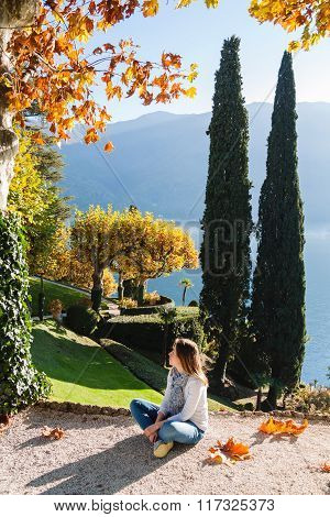 Young girl sitting on the pathway in park of Villa Balbianello in Lenno Lake Como Italy