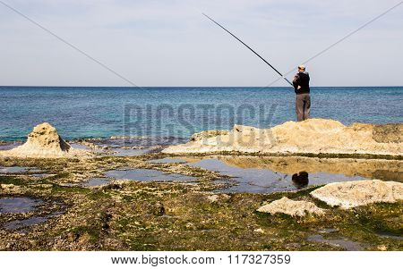 The fisherman is fishing on the shore of the Mediterranean Sea