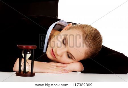 Young business woman sleeping on the desk with hourglass