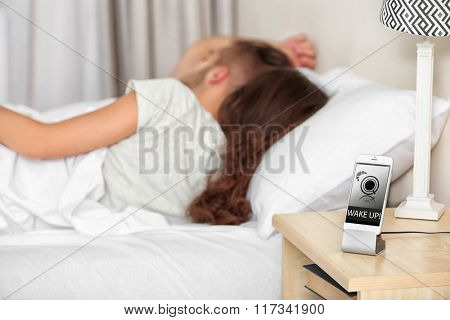 Happy couple waking up with mobile alarm clock