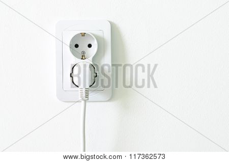European White Electrical Outlet Socket Pluged In On White Wall