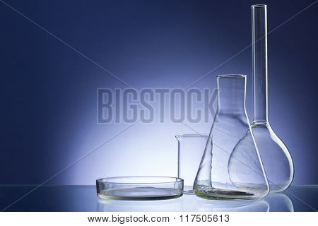 Assorted empty laboratory glassware, test-tubes. Blue tone medical background. Copy space for text.