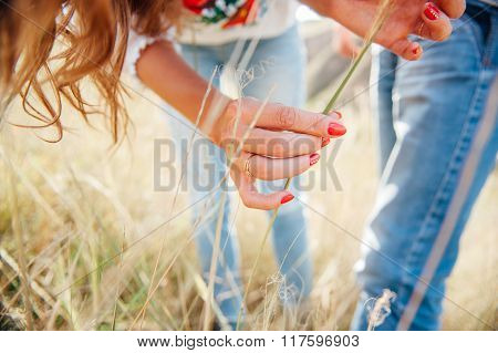 girl touching hands in the national costume of grass spikelets at sunset