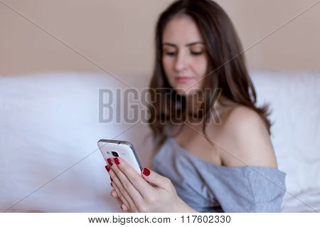 Woman typing messages on her white smartphone