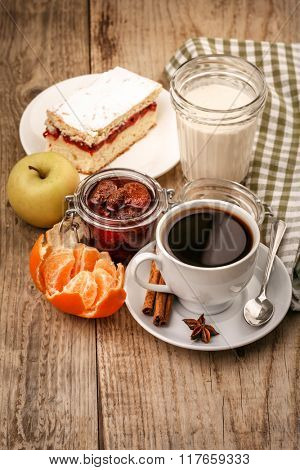 Morning breakfast with hot coffee and joghurt. Fruits tangerines. Lemon. Apple and sweet cake on wooden board in rustic style