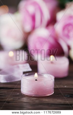 Pink Roses And Pinl Candles On The Wooden Table