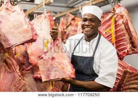 smiling african butcher handing beef in slaughterhouse