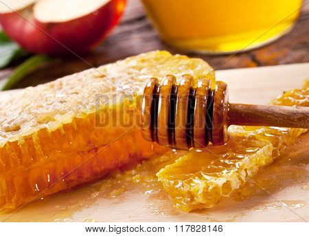 Honeycombs and wooden dripper. Can and apple on the background.