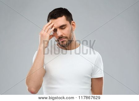 health care, pain, stress and people concept - young man suffering from headache