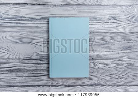Blank book cover on textured wood background. Copy space