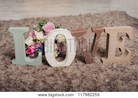 Vintage wooden inscription Love with flowers on the brown background