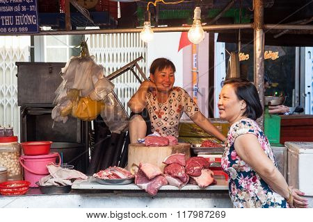 Two women are having a conversation at the wet market