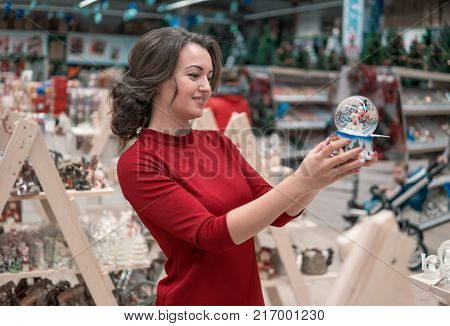 Cheerful happy customer girl choosing gifts for Christmas and New Year. She is taking ball with the snow