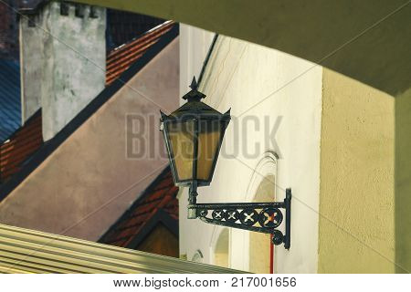 Lantern on a yellow wall against a background of roofs and chimneys in Old Riga