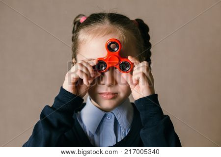 Little caucasian school girl with Fidget Spinner held up to his eyes
